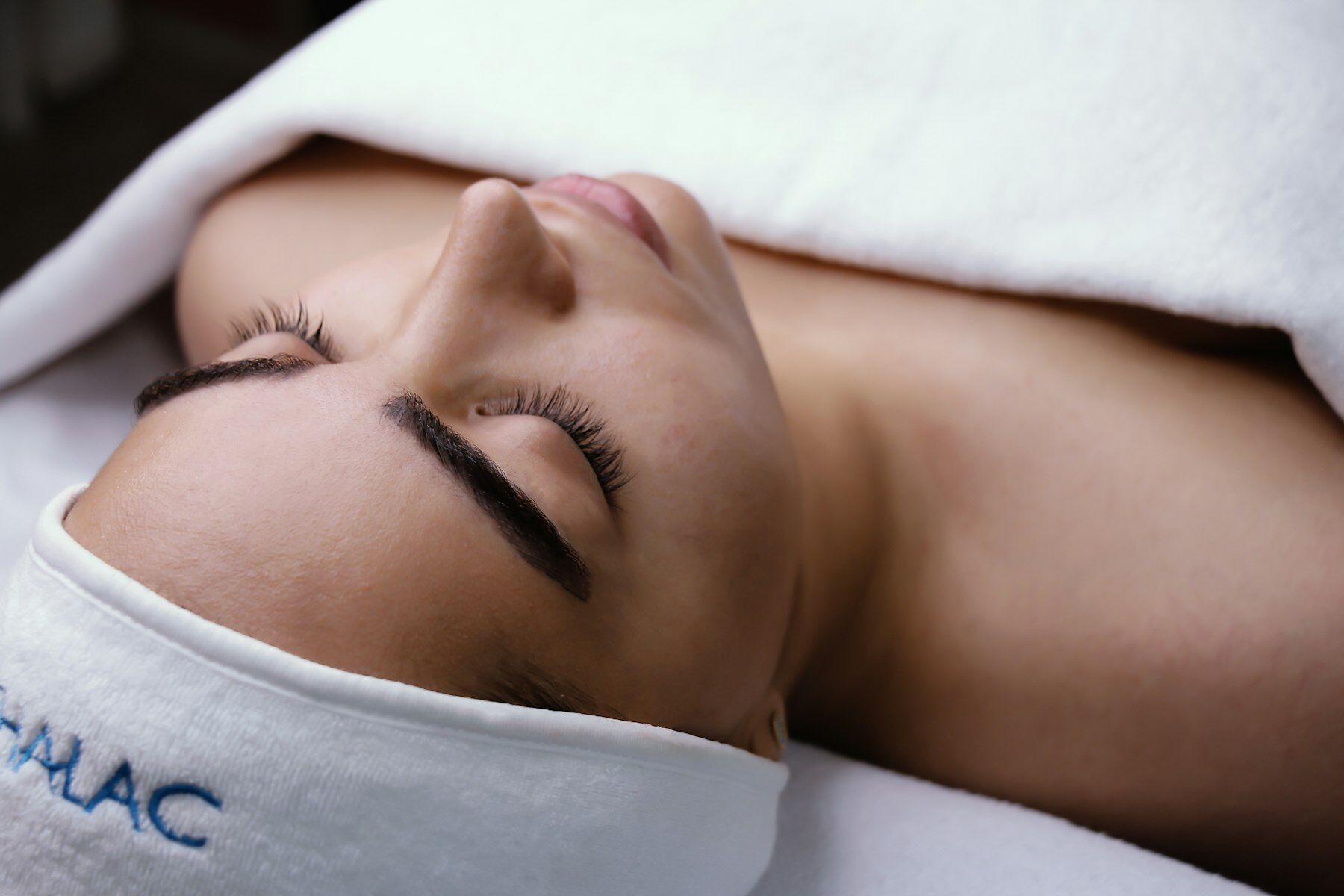 Guest relaxing on a white towel during a facial